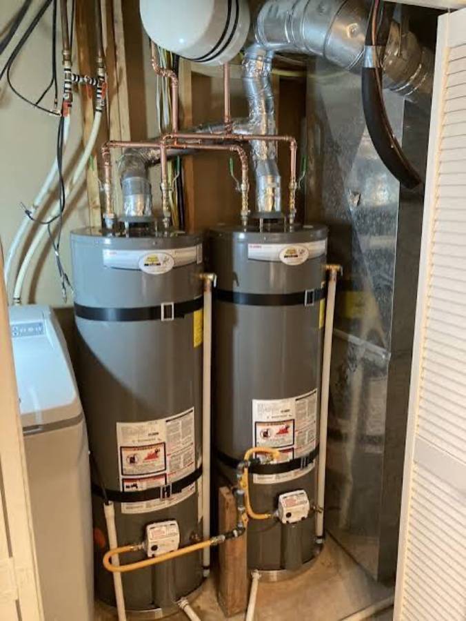 Basement plumbing area with multiple water heaters and exposed piping used as hero image for plumbing and drain cleaning services